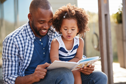 Un papa cherche des lettres dans un livre avec sa fille