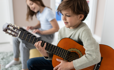 Enfant qui apprend à jouer de la guitare