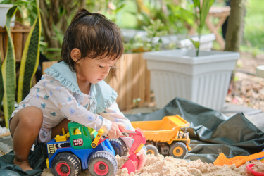 Petite fille qui joue avec des camions