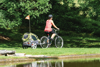 Une maman roule avec son enfant dans une remorque à vélo