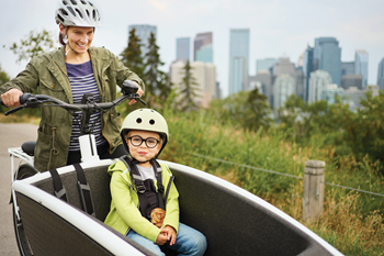 Une maman transporte son garçon dans un vélo cargo