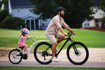 Un papa pédale avec sa fille installée sur un demi-vélo