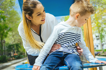 Petit garçon au parc qui refuse de faire ce que sa mère lui demande