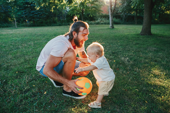 Un papa joue au ballon dehors avec son bébé Un papa joue au ballon dehors avec son bébé